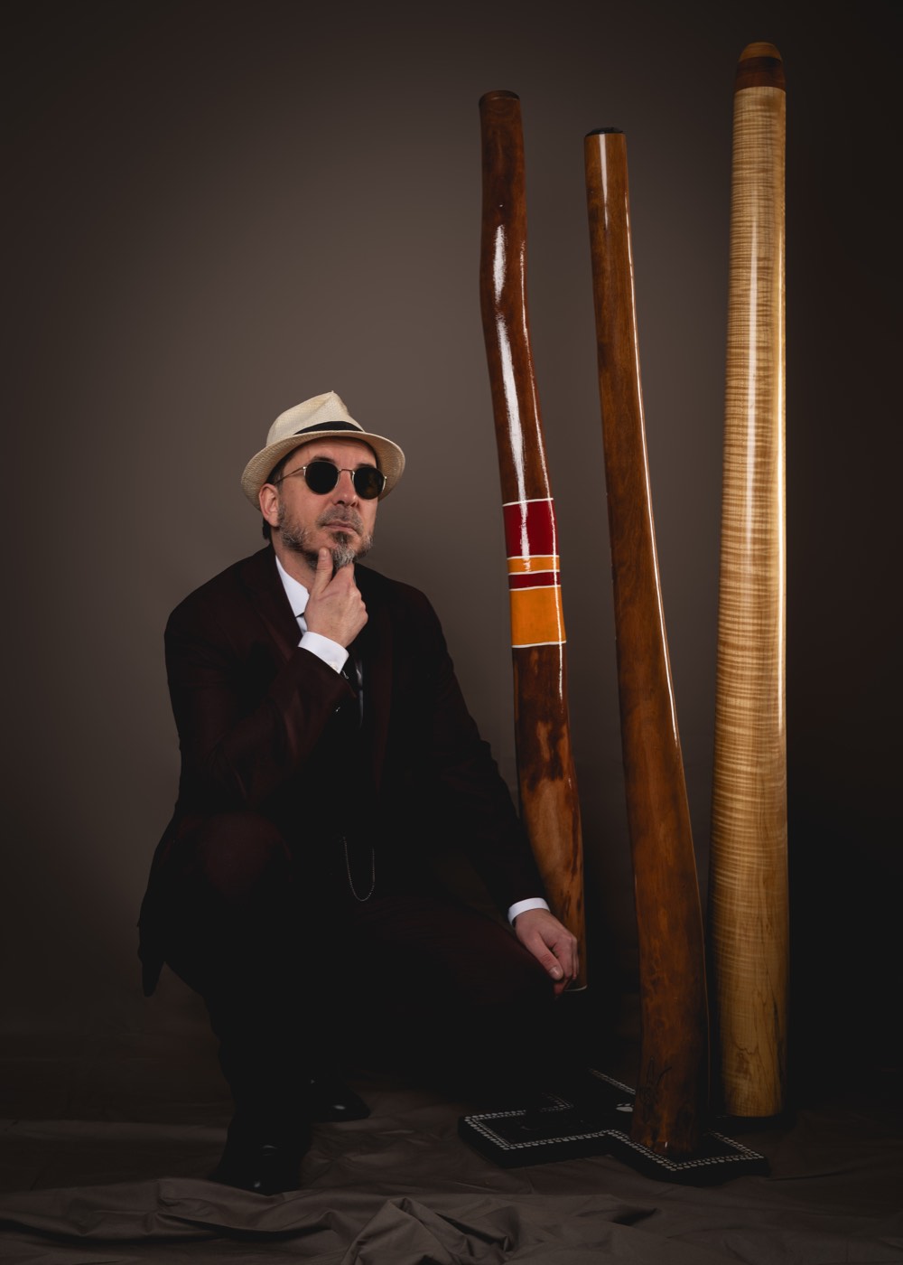 Triton Squad, fondateur de Maximum Didgeridoo, accroupi devant trois didgeridoos